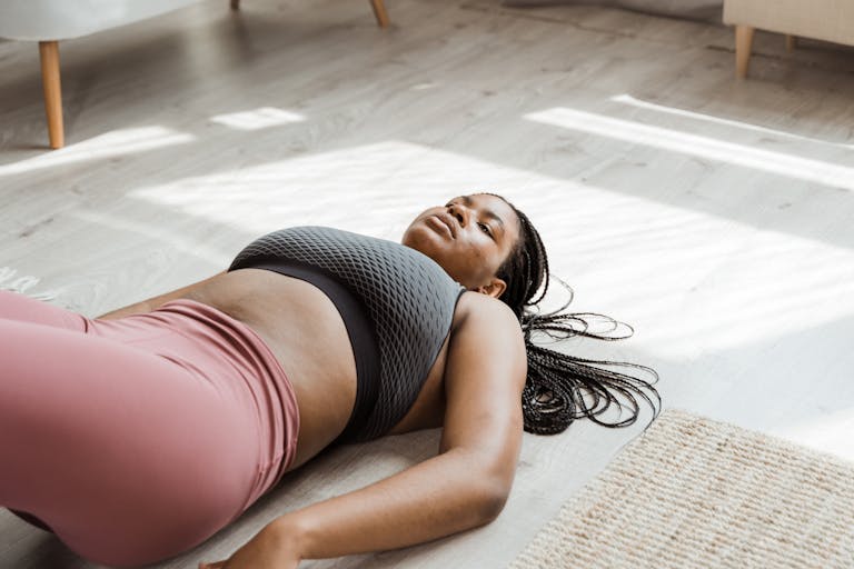 Woman in activewear relaxing on a gym mat indoors, highlighting self-care and fitness.